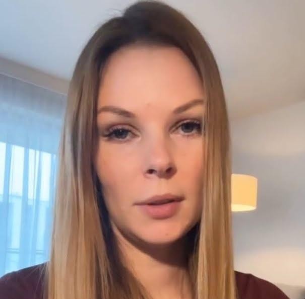 Małgorzata Tomaszewska w swobodnej pozie, przeglądająca telefon i uśmiechająca się, symbolizująca jej aktywność na Instagramie.