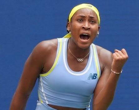 Coco Gauff uśmiechnięta, trzymająca rakietę tenisową, poza kortem.