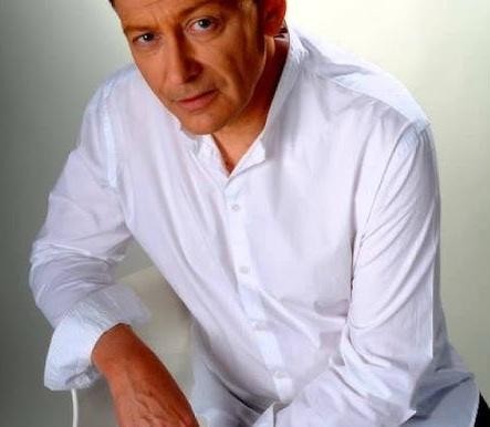Jacek Borkowski, polski aktor, uśmiechnięty i zaangażowany w przygotowywanie posiłku dla rodziny w domowej kuchni, ukazujący jego pasję do gotowania i życie prywatne.