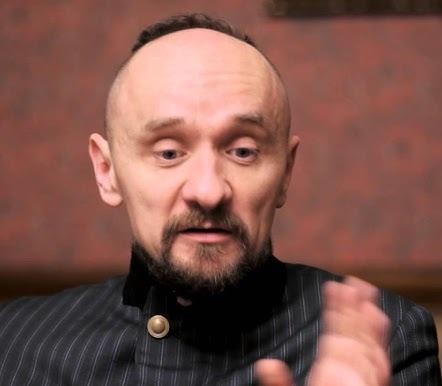 Jan Klata w swobodnej pozie, w tle subtelne ujęcie Warszawy, miejsca jego zamieszkania.