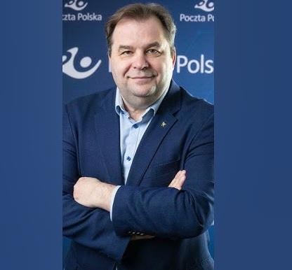 Sebastian Mikosz w biurze, gestykulujący przed ekranem z danymi lotniczymi, symbolizującym jego rolę w restrukturyzacji linii lotniczych.