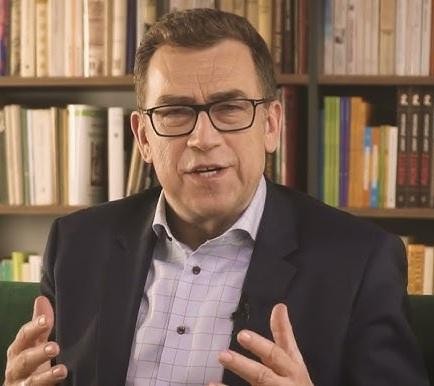 Maciej Orłoś czytający książkę dwójce uśmiechniętych dzieci, symbolizujący jego twórczość dla najmłodszych.