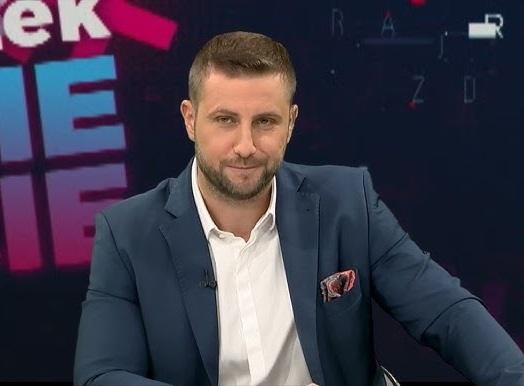 Alt: Miłosz Kłeczek w studiu telewizyjnym podczas dynamicznej pracy dziennikarskiej.